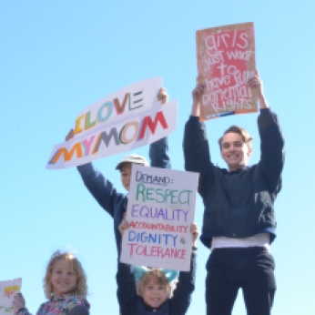 Children hold up signs as the crowd cheers at the Los Angeles Women's March on January 20, 2018 in Los Angeles, CA (Photo by Breanna Reeves).
